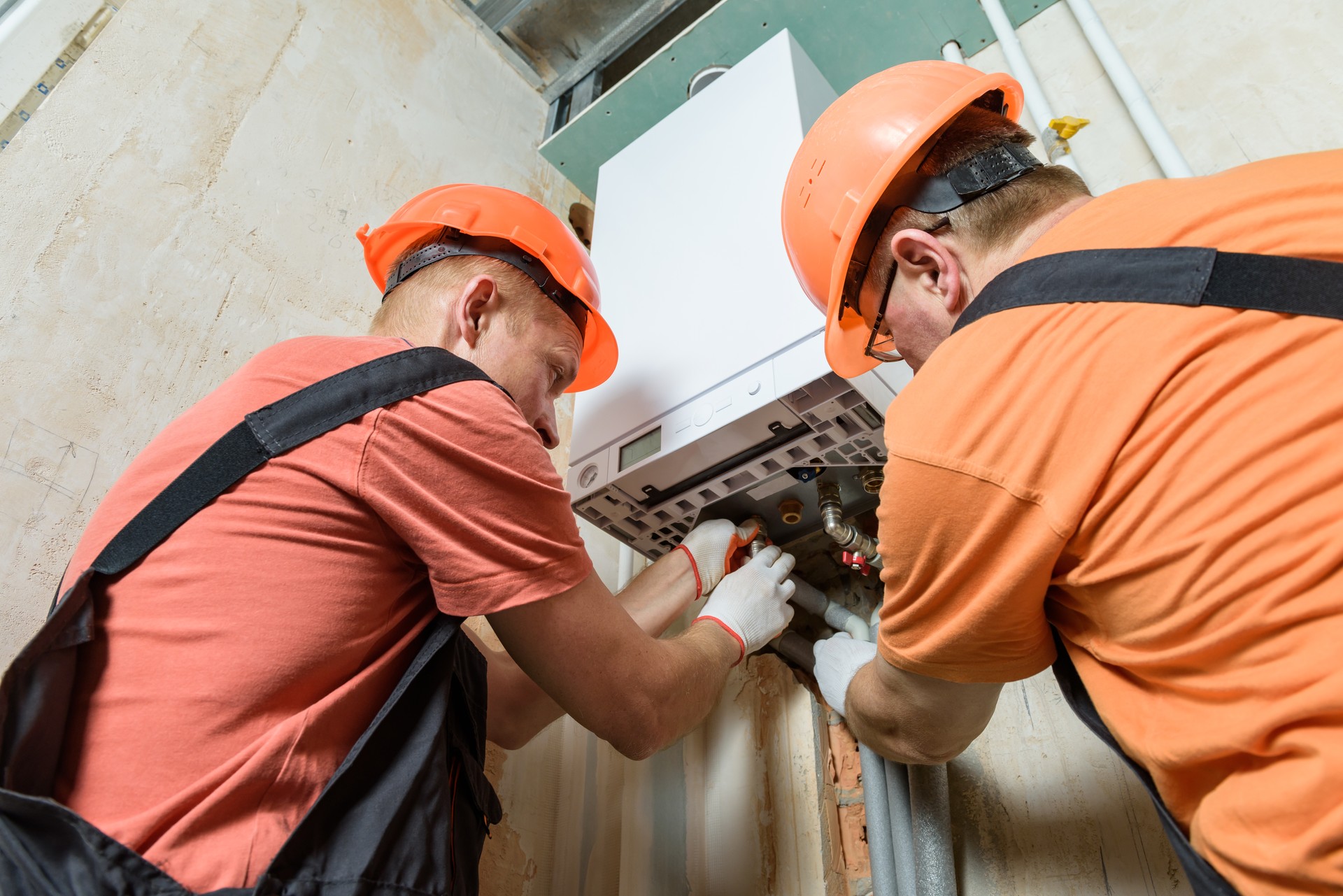 Workers are connecting the pipes to the gas boiler.